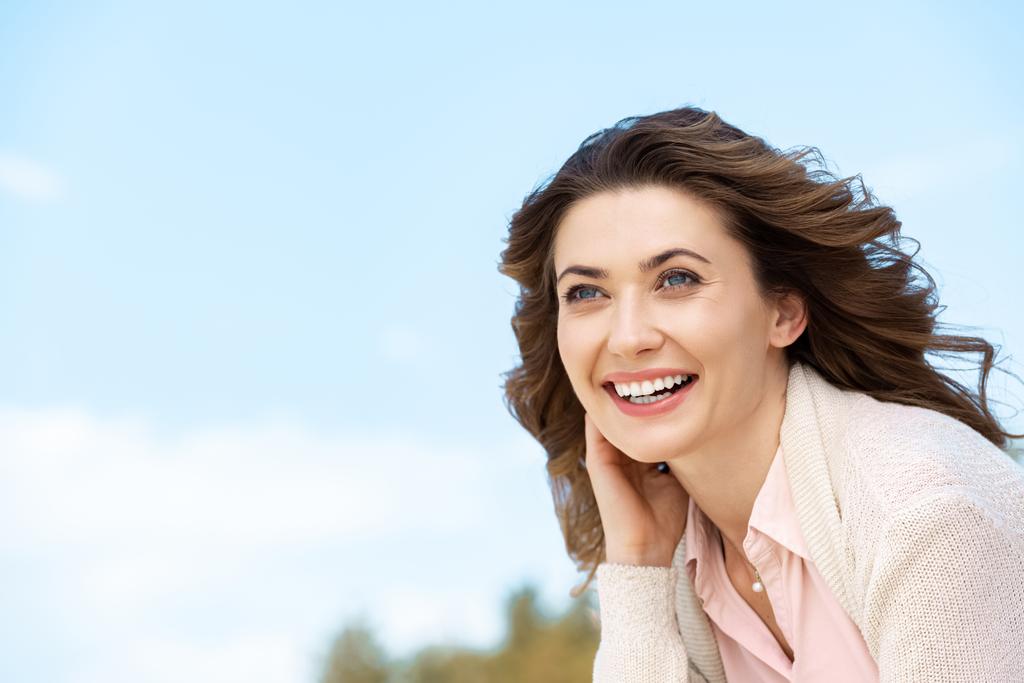 retrato de mujer hermosa sonriente con cielo azul nublado en el fondo
 - Foto, Imagen