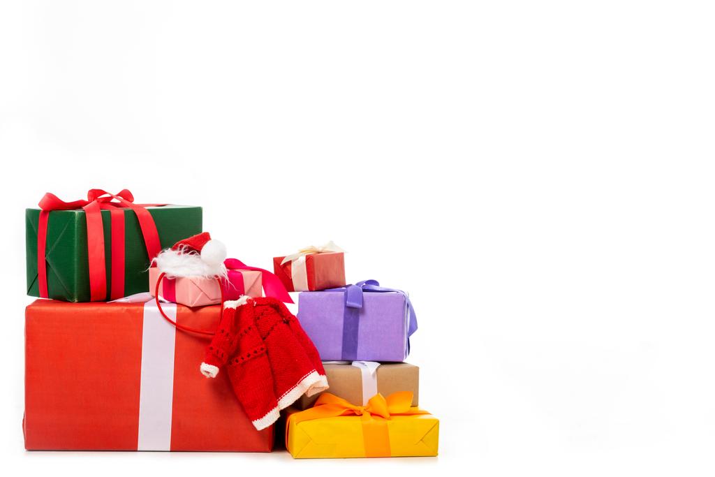 Χριστουγεννιάτικο καπέλο και γιλέκο στο σωρό κουτιά δώρων που απομονώνονται σε λευκό φόντο  - Φωτογραφία, εικόνα