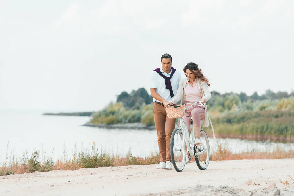 muž pomáhá manželka ride retro kolo na písečné řeky  - Fotografie, Obrázek
