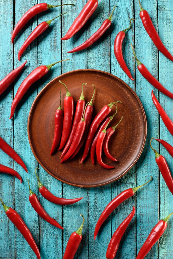 felülnézet érett piros chili paprika, a lemez és a kék fa tábla - Fotó, kép