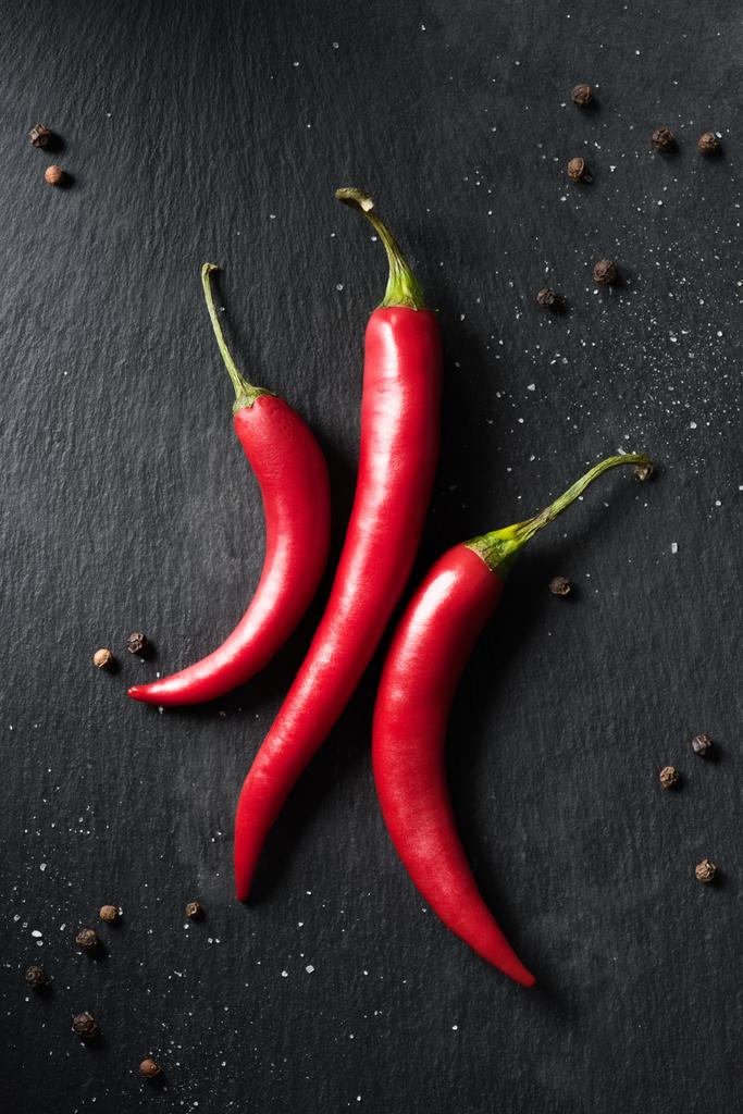 ylhäältä näkymä kolme punaista kypsää chiliä mustalla pinnalla
 - Valokuva, kuva