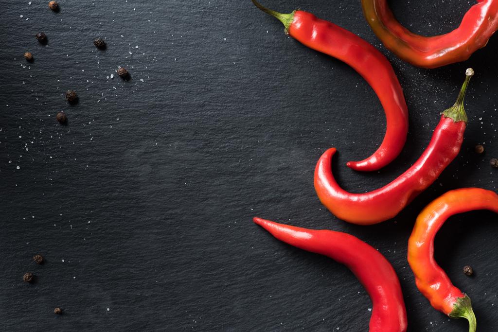 podniesionymi widokiem czerwone papryki chili ekologicznej na czarnej powierzchni - Zdjęcie, obraz