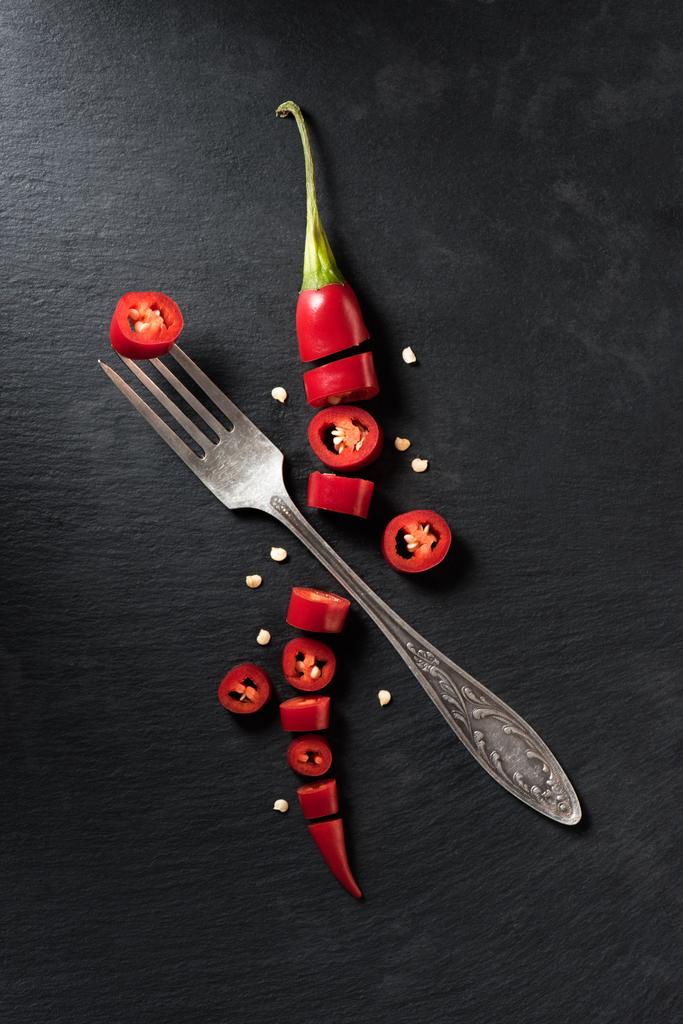 podwyższone widok cut czerwony dojrzałe papryczki chili i widelec na czarnej powierzchni - Zdjęcie, obraz
