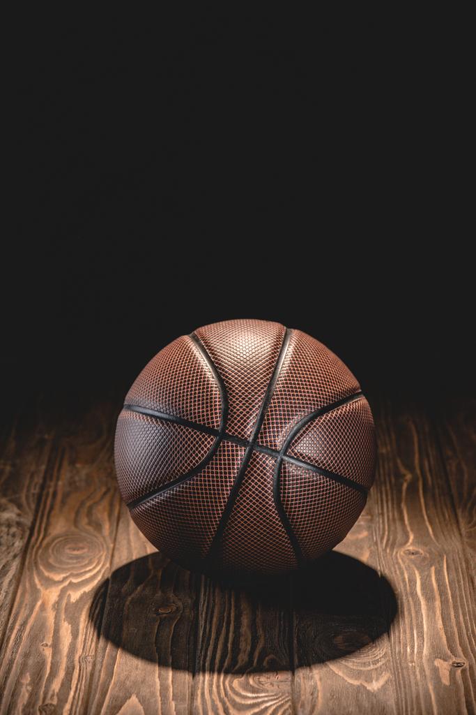 egy gumi kosárlabda labda a sötét szobában fa padló - Fotó, kép