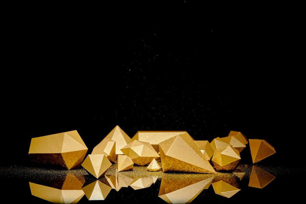glanzende faceted gouden stukken en stof weerspiegeld op zwarte achtergrond  - Foto, afbeelding