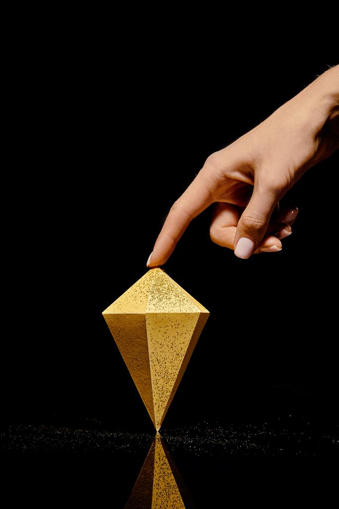 обрізаний знімок руки, що торкається шматка золота на чорному
 - Фото, зображення