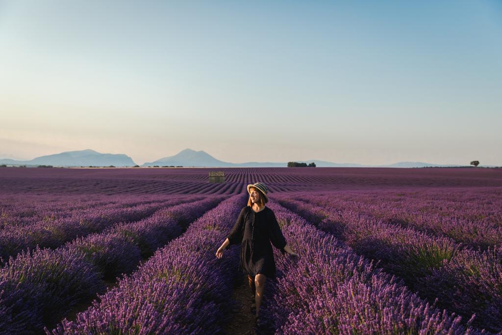 beautiful young woman walking between blooming lavender flowers, provence, france - Photo, Image
