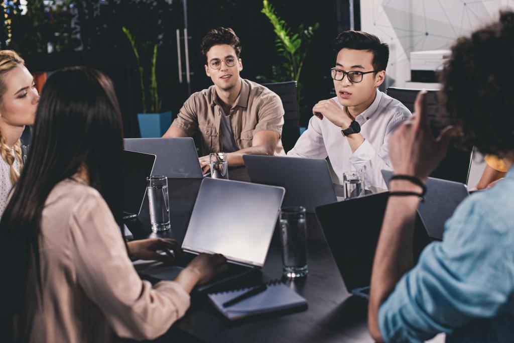 groupe multiculturel de partenaires d'affaires ayant une discussion à table avec des ordinateurs portables dans le bureau moderne
  - Photo, image