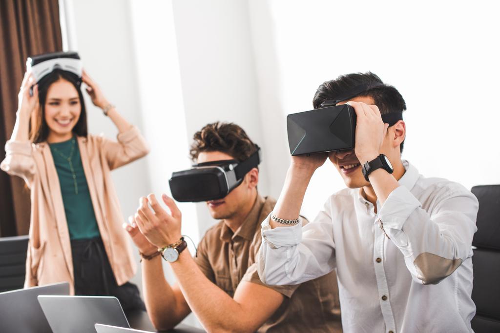 twee lachende zakenlieden met behulp van virtuele realiteit headsets op moderne kantoor  - Foto, afbeelding