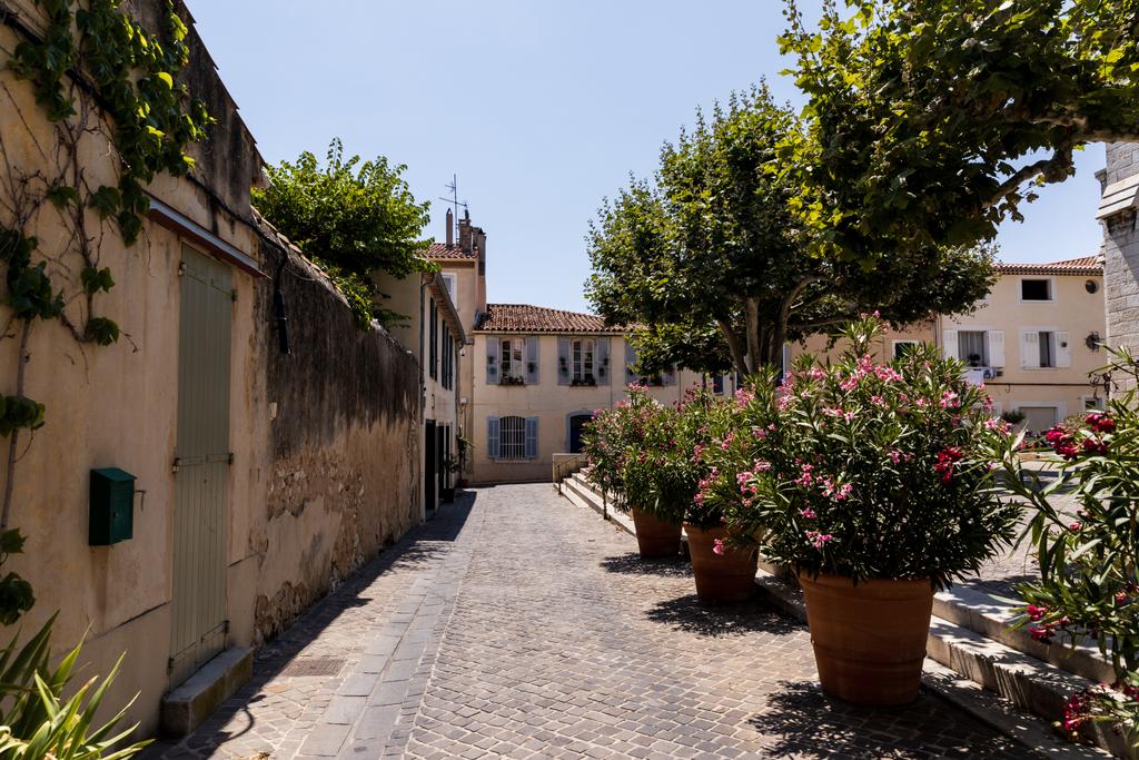 gyönyörű hangulatos szűk utcában a hagyományos házak, a zöld fák és a virágzó virágok cserépben, provence, Franciaország - Fotó, kép