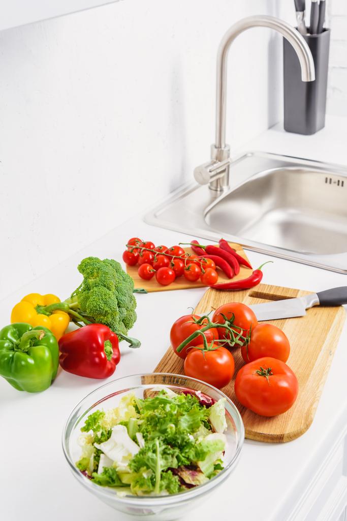 heerlijke tomaten en chilipepertjes op snijplanken in lichte keuken  - Foto, afbeelding