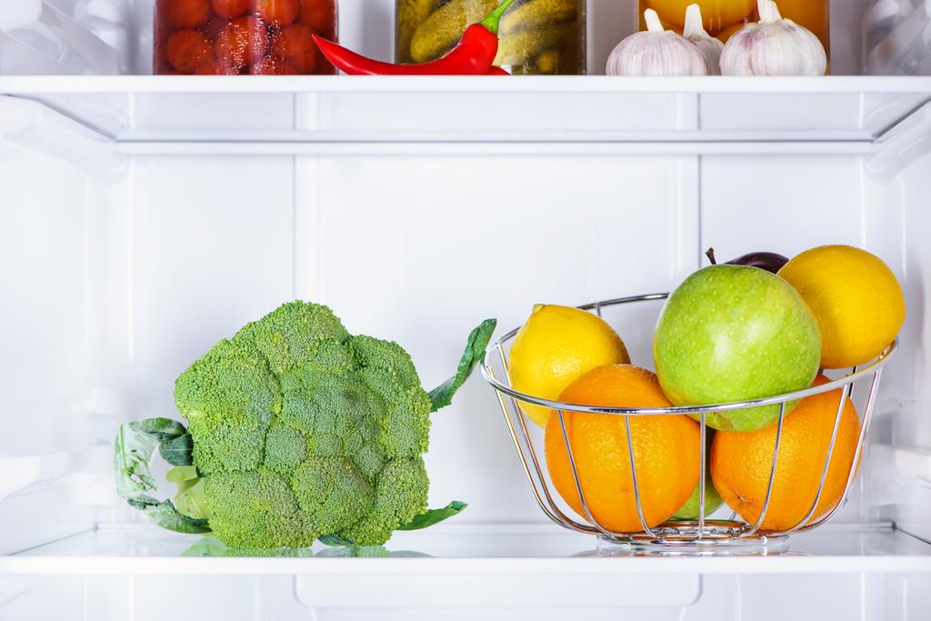 broccoli en rijpe smakelijke vruchten in koelkast - Foto, afbeelding