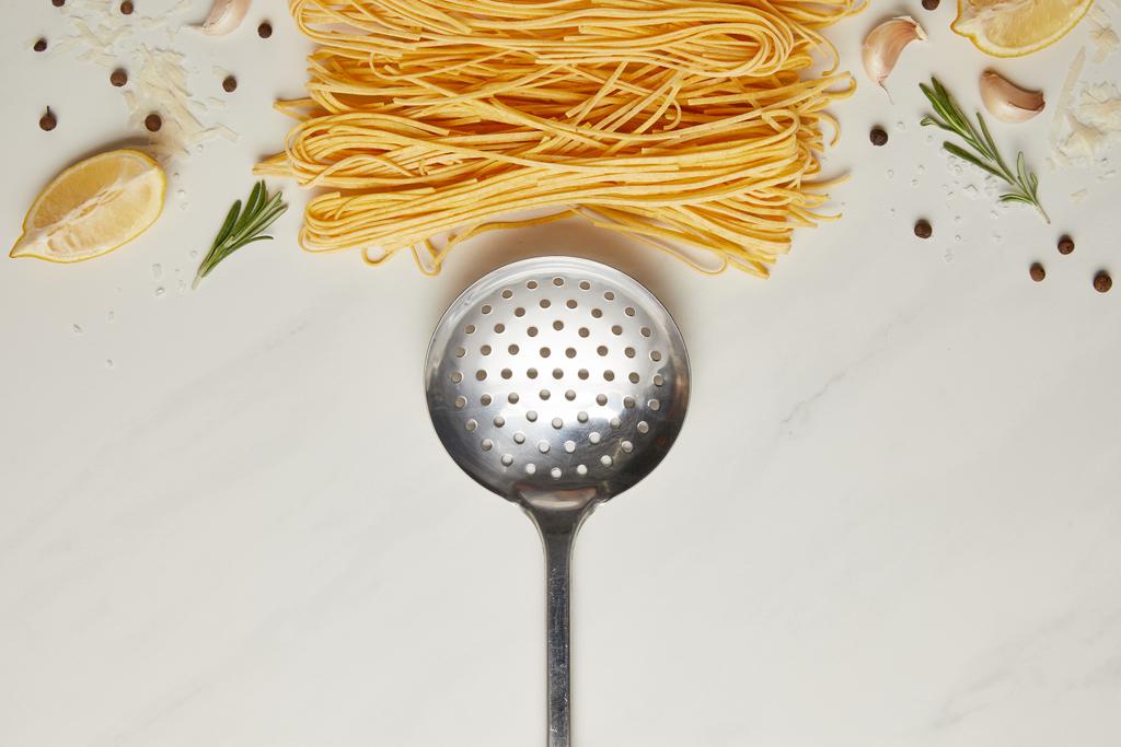 сверху вид на ковш и итальянские ингредиенты пасты на белом мраморном столе
 - Фото, изображение