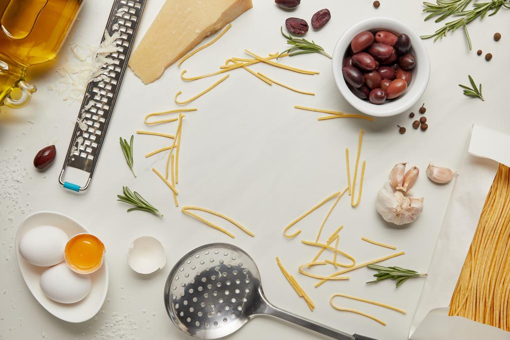 flat lay with italian pasta ingredients, ladle and grater arranged on white tabletop - Photo, Image