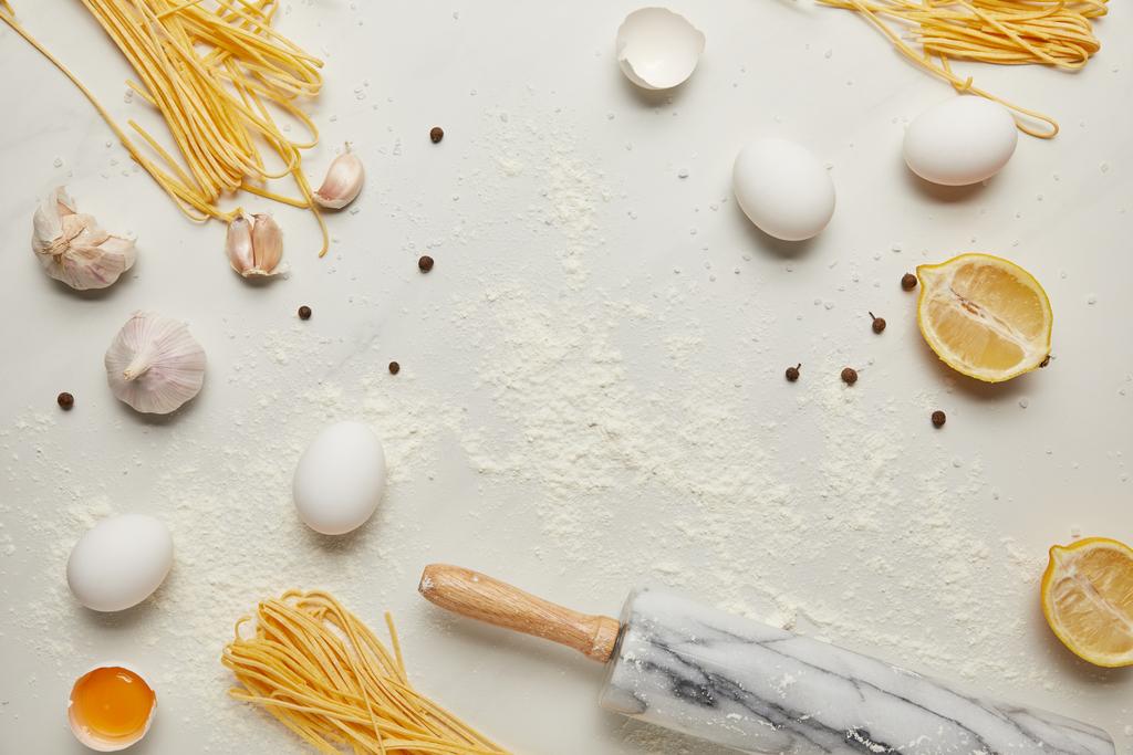 tendido plano con rodillo e ingredientes para pasta italiana dispuestos en la mesa de mármol blanco
 - Foto, Imagen