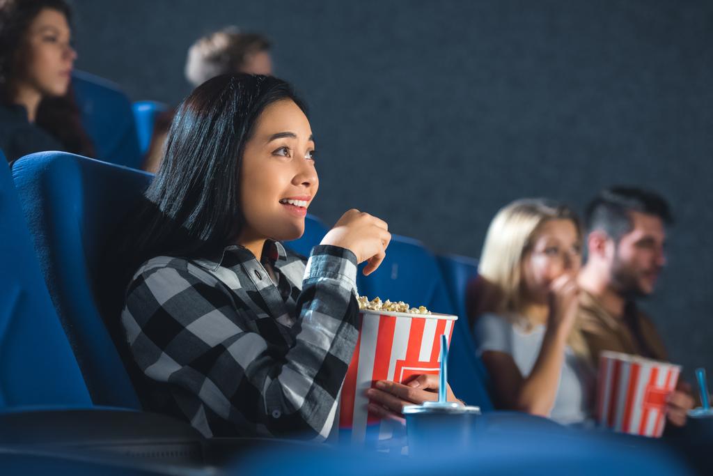 emotional asian woman with popcorn watching movie in cinema - Photo, Image