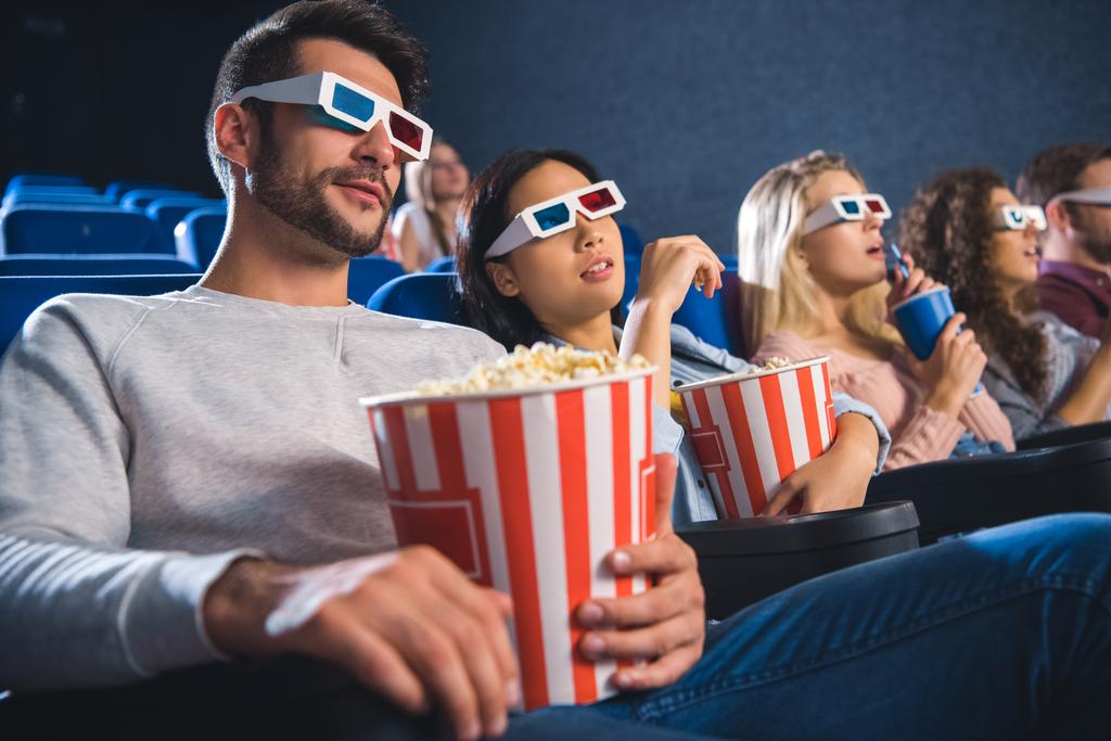 multiethnic friends in 3d glasses with popcorn watching film together in movie theater - Photo, Image