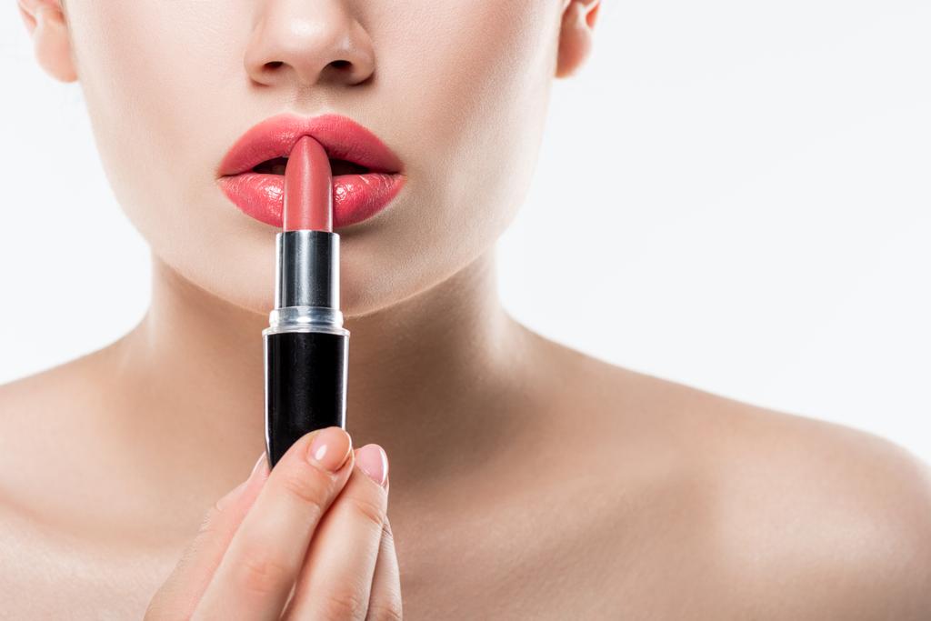 vue recadrée d'une jeune femme appliquant du rouge à lèvres rose, prise de vue studio isolée sur blanc
 - Photo, image