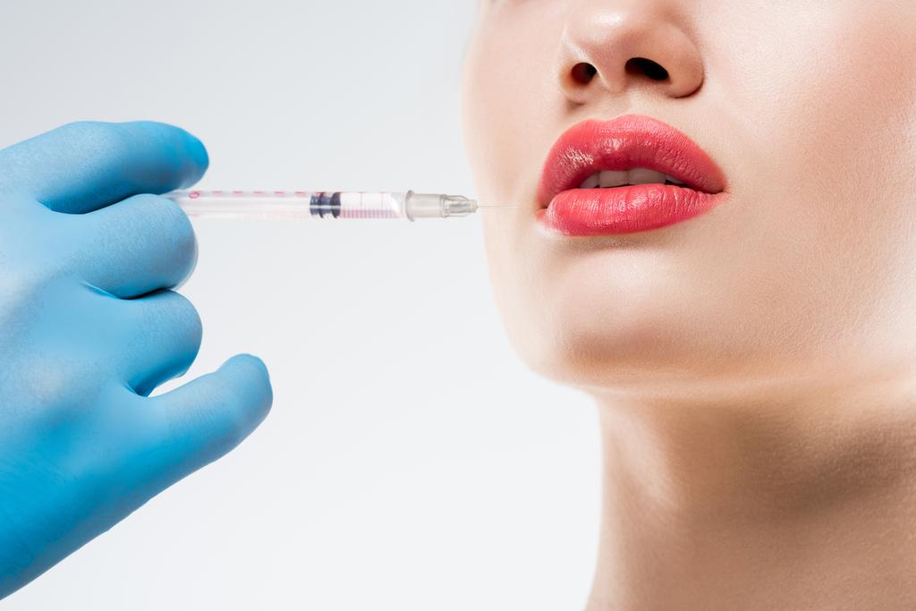 女性は、白で隔離のための唇の美容注射を行う医師のトリミング ビュー - 写真・画像