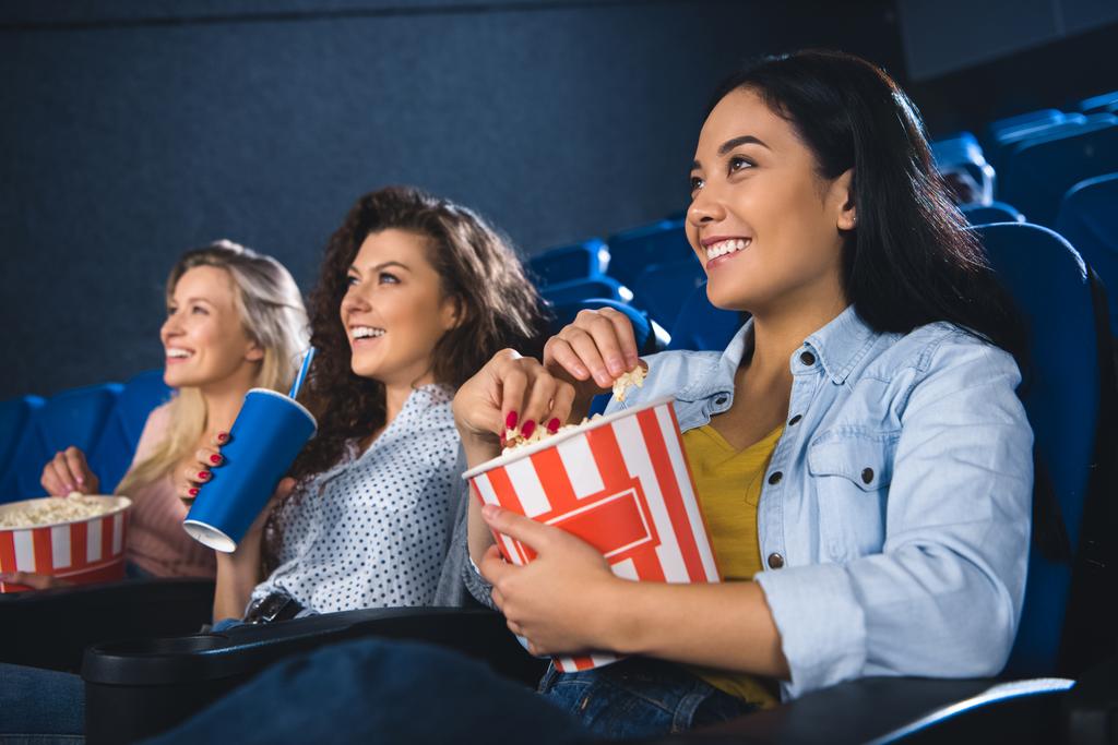 glimlachend multiraciale vrouwen met popcorn kijken film samen in de bioscoop - Foto, afbeelding