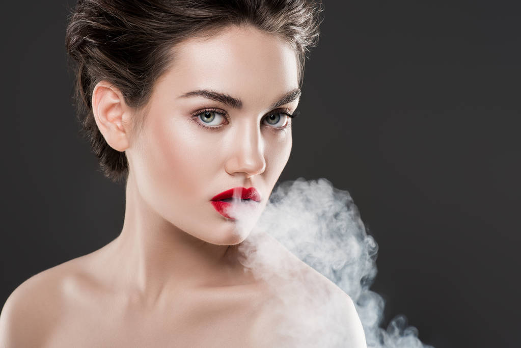 beautiful fashionable woman blowing smoke, isolated on grey - Photo, Image