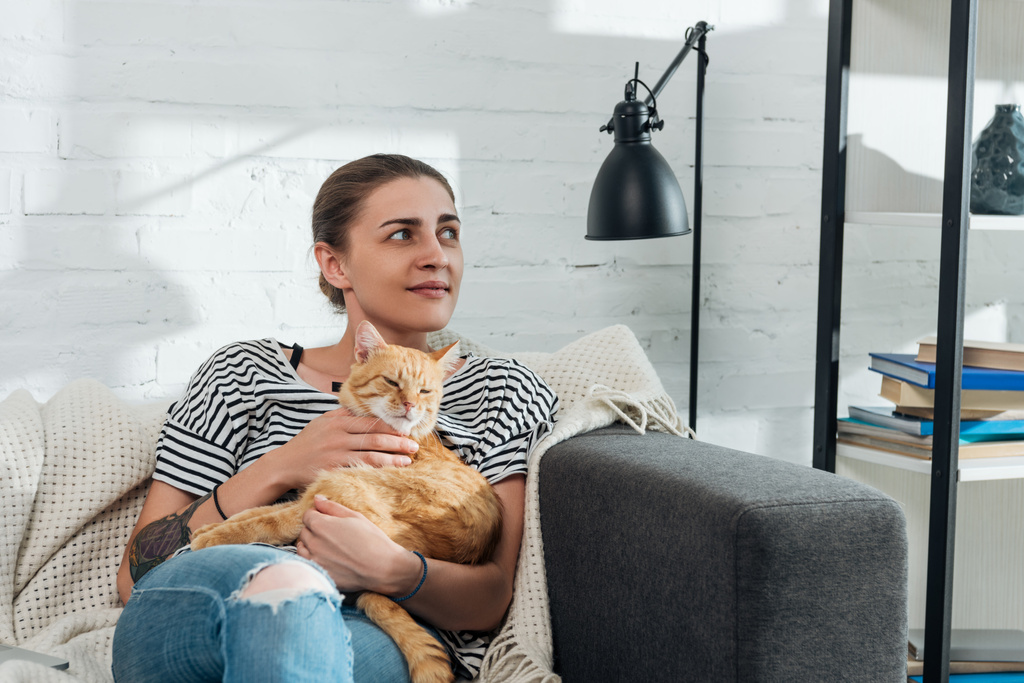 krásná s úsměvem mladá žena hospodářství červená kočka a koukal doma - Fotografie, Obrázek