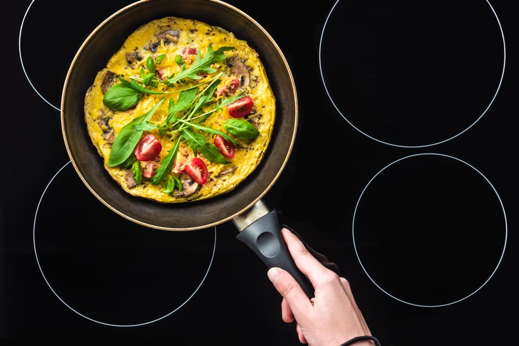 przycięte zdjęcie kobieta gotowania omlet na patelni na czarny piec - Zdjęcie, obraz