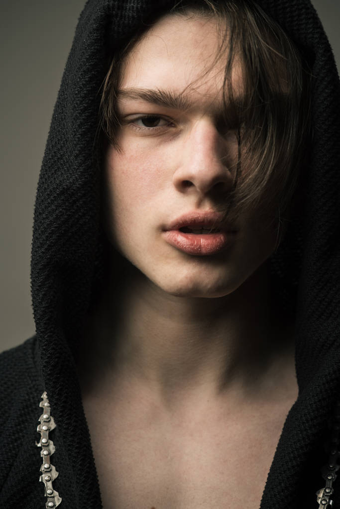 Closeup portret van tiener dragen zwarte kap. Jonge man met halflang haar en volle lippen zingen rap, hiphopcultuur en jeugd stijl concept - Foto, afbeelding