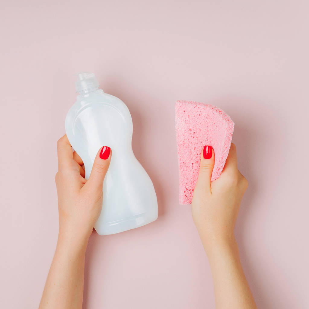 weibliche Hände mit Reinigungsmittel und Schwamm auf rosa Hintergrund - Foto, Bild