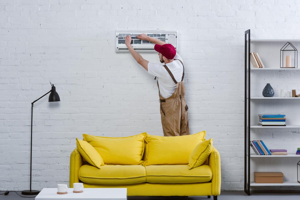 profissional reparador mudando filtro para ar condicionado pendurado na parede de tijolo branco
 - Foto, Imagem