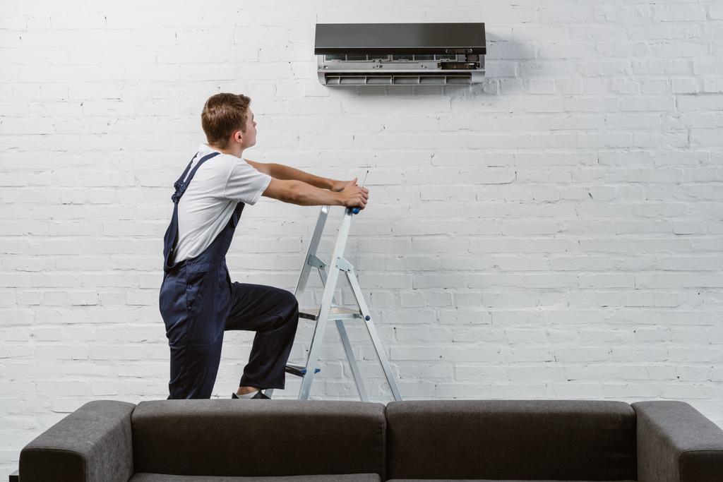 professional air conditioner repairman standing on stepladder - Photo, Image