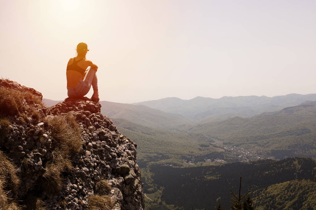 concept de voyage avec dos d'une jeune fille de fitness debout sur un rocher et regardant le paysage de montagne
 - Photo, image