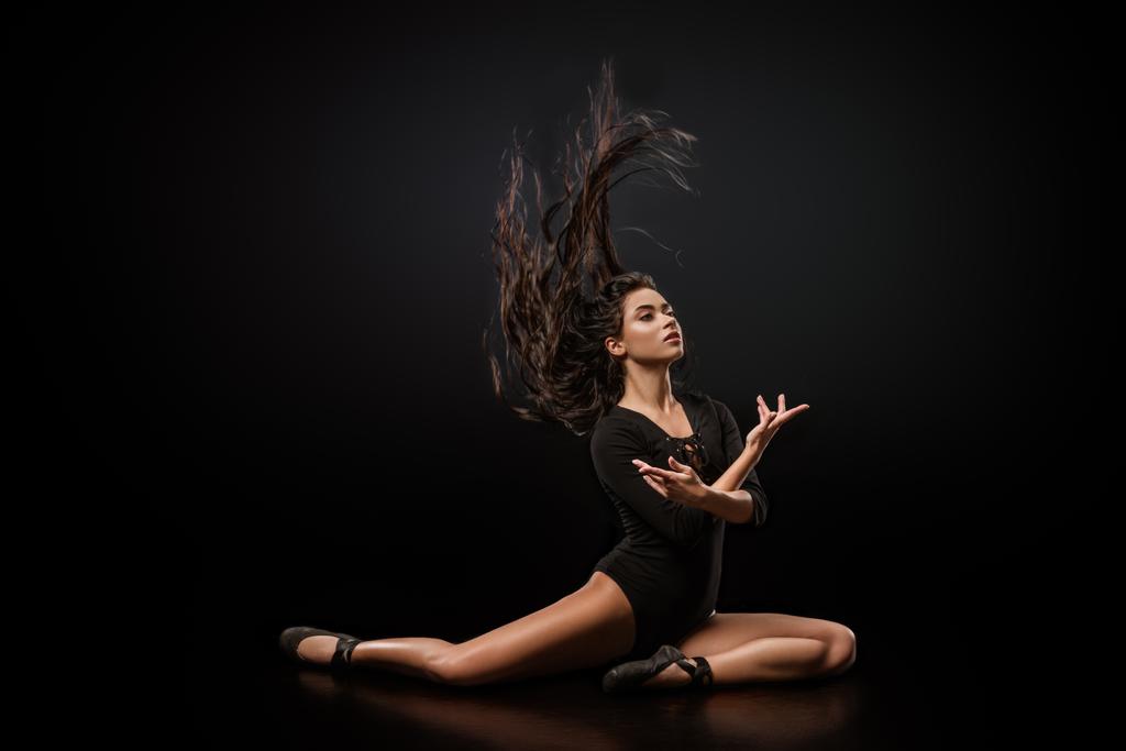 junge attraktive Ballerina in schwarzem Body und Ballettschuhen posiert vor dunklem Hintergrund - Foto, Bild