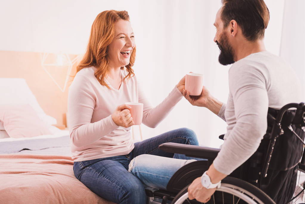 Mujer feliz bebiendo té con su marido discapacitado
 - Foto, Imagen