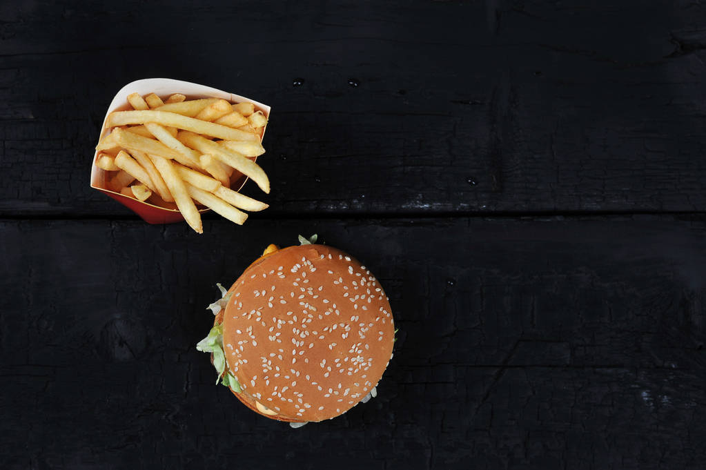 Burger seesami pulla ja ranskanperunoita musta tausta ylhäältä, tasainen kerros, copyspace
 - Valokuva, kuva