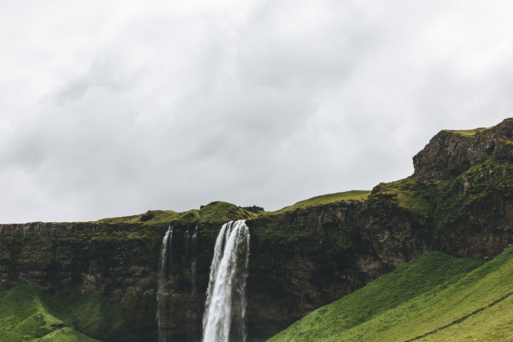 scenic view of landscape with Seljalandsfoss waterfall in highlands under cloudy sky in Iceland  - Photo, Image