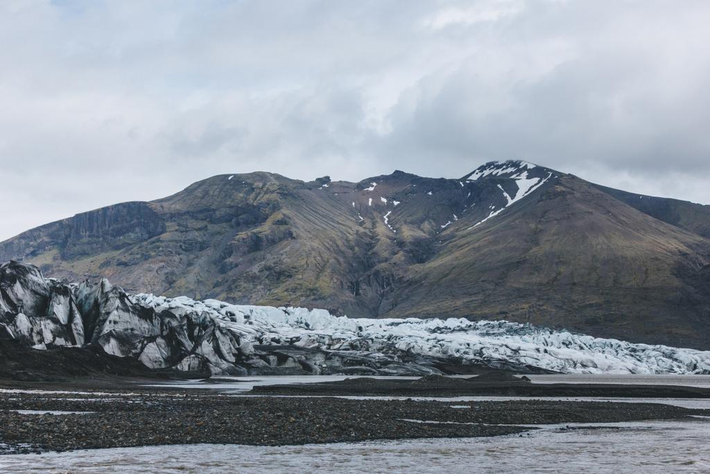 παγετώνας Skaftafellsjkull και τα χιονισμένα βουνά εναντίον συννεφιασμένο ουρανό στο Εθνικό Πάρκο Σκαφτάφελλ στην Ισλανδία  - Φωτογραφία, εικόνα