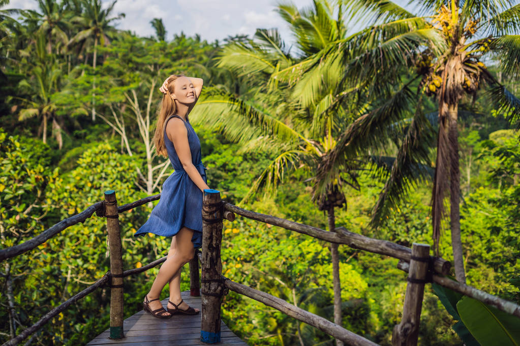Mujer joven viajera posando en el punto de vista con las selvas en el fondo, Bali, Indonesia
. - Foto, imagen