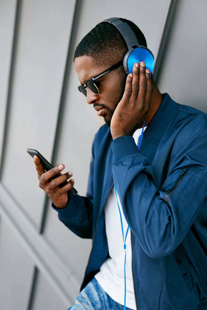Hombre escuchando música en los auriculares en el teléfono en la calle
.  - Foto, Imagen
