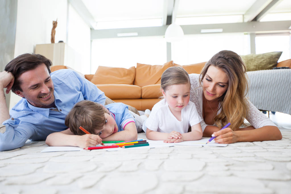 Urocza rodzina z dziećmi rysującymi razem na podłodze w salonie - Zdjęcie, obraz