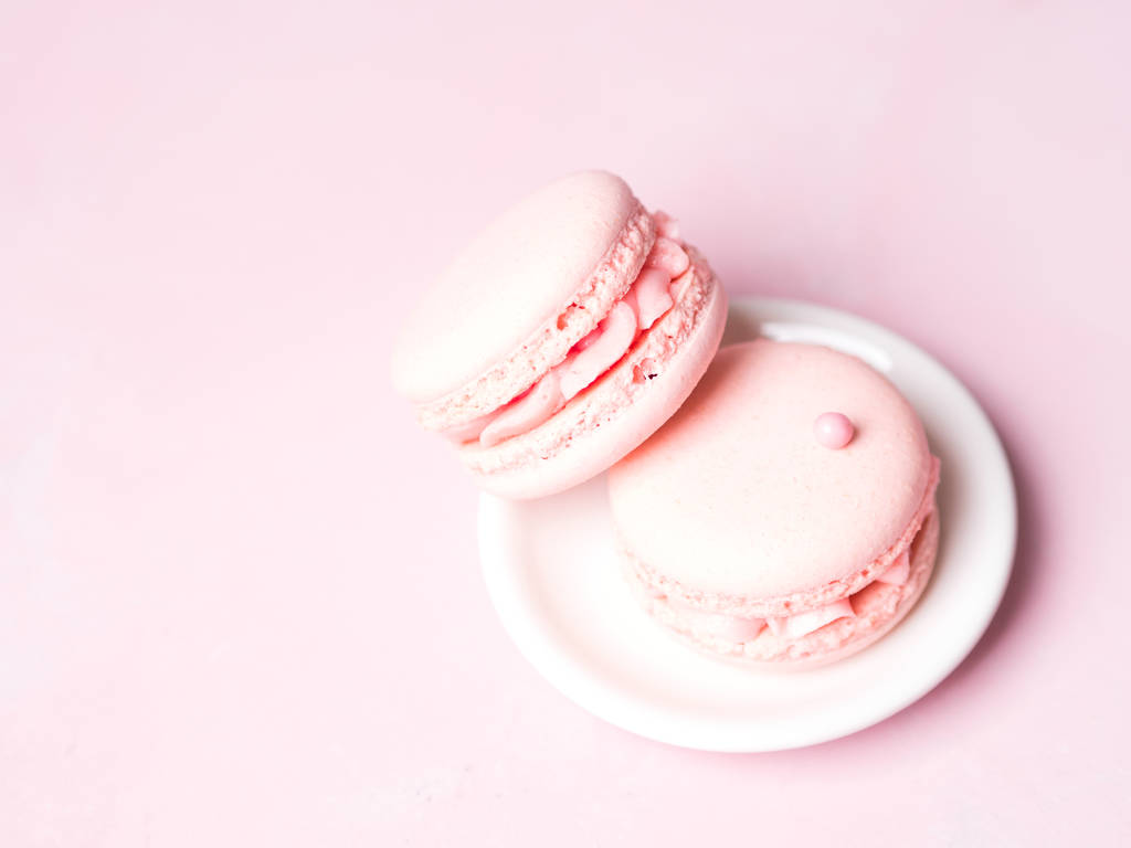French strawberry macaroons on saucer over pink pastel background - Photo, Image