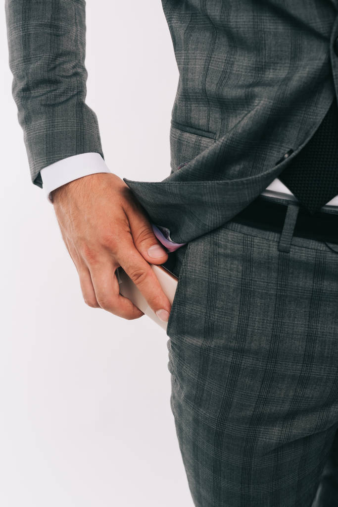 imagen recortada de hombre de negocios poniendo teléfono inteligente en el bolsillo aislado en blanco
 - Foto, imagen