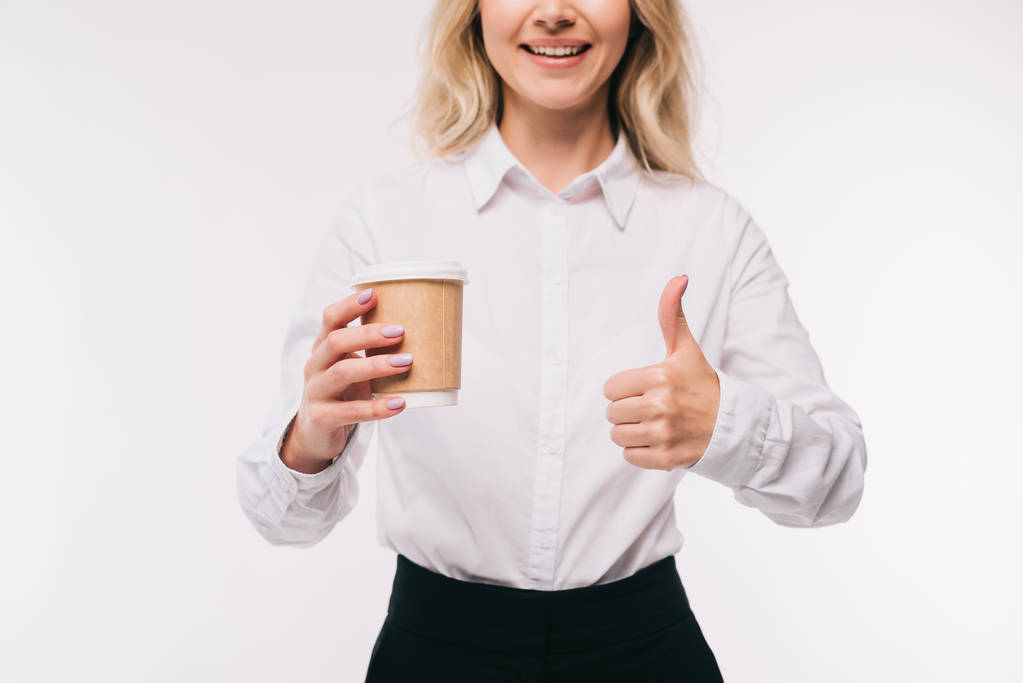 bijgesneden afbeelding van zakenvrouw holding wegwerp koffiekopje en weergegeven: duim omhoog geïsoleerd op wit - Foto, afbeelding