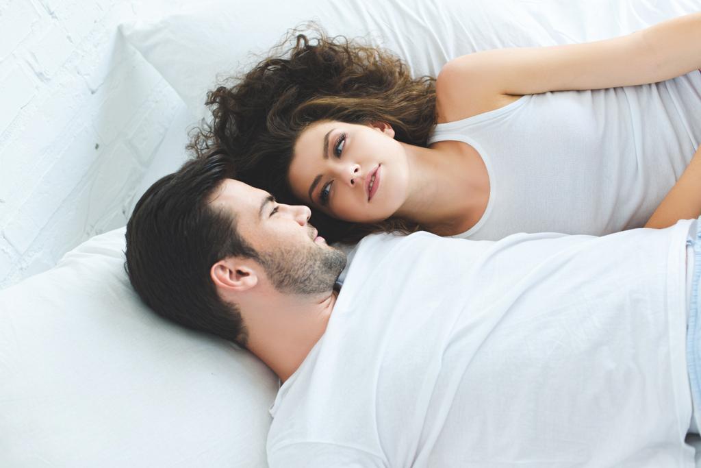 vysoký úhel pohled krásný mladý pár leží v posteli a při pohledu na sebe  - Fotografie, Obrázek