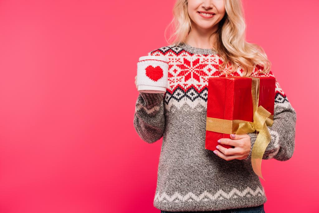 image recadrée de femme souriante dans un pull tenant tasse et boîte cadeau isolé sur rose
 - Photo, image