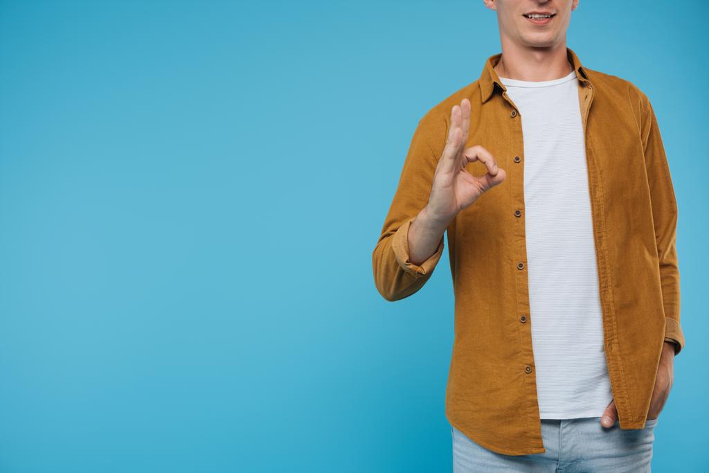 abgeschnittenes Bild eines Mannes, der auf blauem Grund seine Okay-Geste zeigt - Foto, Bild