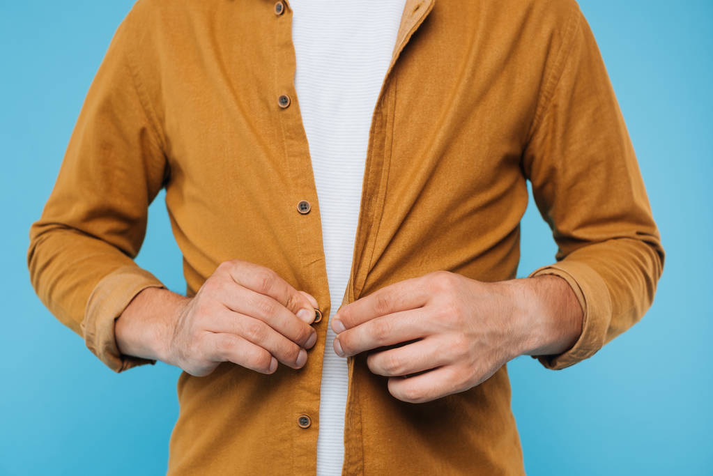 cropped image of man buttoning brown shirt isolated on blue - Photo, Image