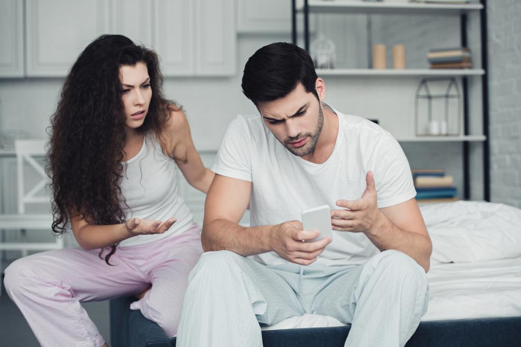 расстроены молодые пары ссорятся в то время как человек с помощью смартфона, отношения трудности концепция
 - Фото, изображение