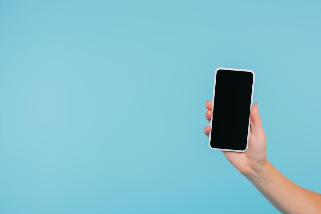 cropped image of girl holding smartphone with blank screen in hand isolated on blue - Photo, Image