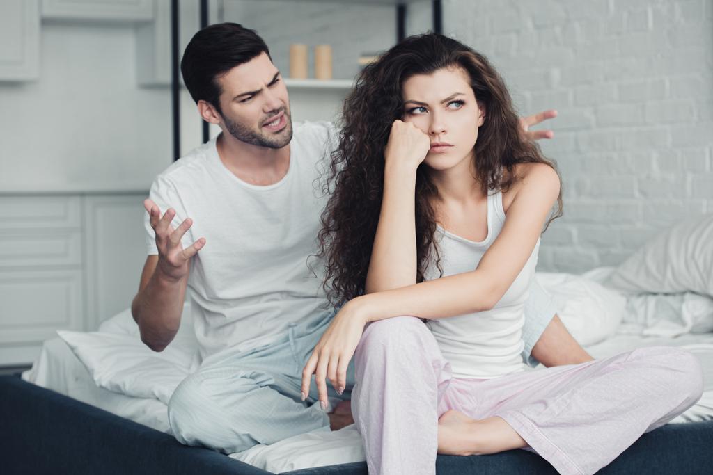 jeune couple en pyjama assis sur le lit et querelles, concept de difficultés relationnelles
 - Photo, image